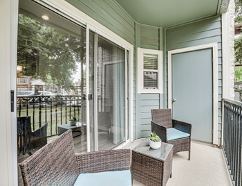 a screened in porch with two wicker chairs and a small table with a potted plant  at Limestone Ranch, Lewisville